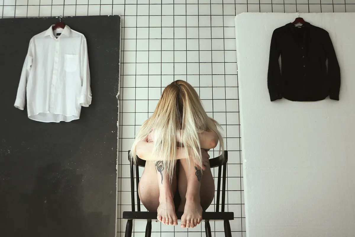 A woman sitting on a chair covering her face