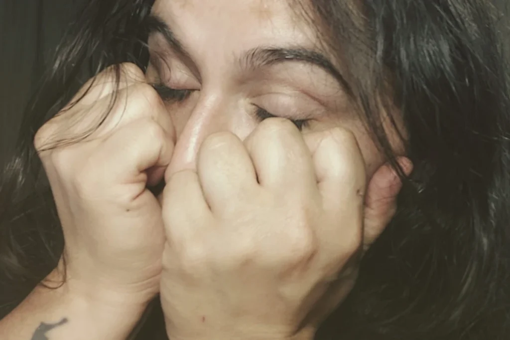 sandra holding her face in her hands with closed fists